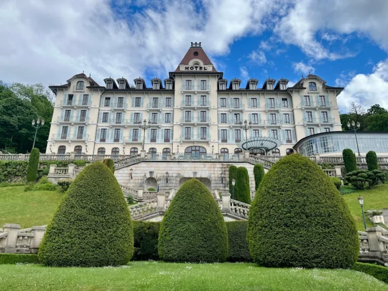 Elegant historical hotel facade in Menthon-Saint-Bernard with manicured gardens.