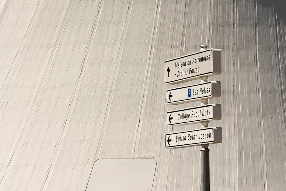 Directional signs in a cityscape setting with modern architectural backdrop.