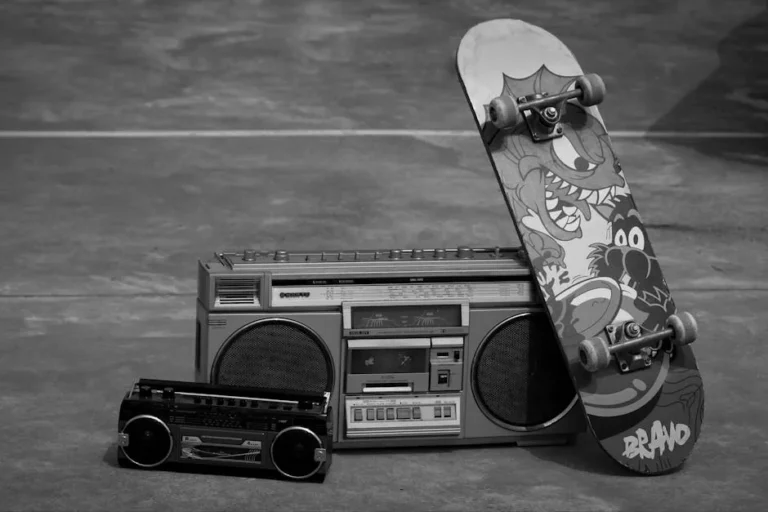 Vintage cassette player and skateboard with graphic design in a black and white setting.